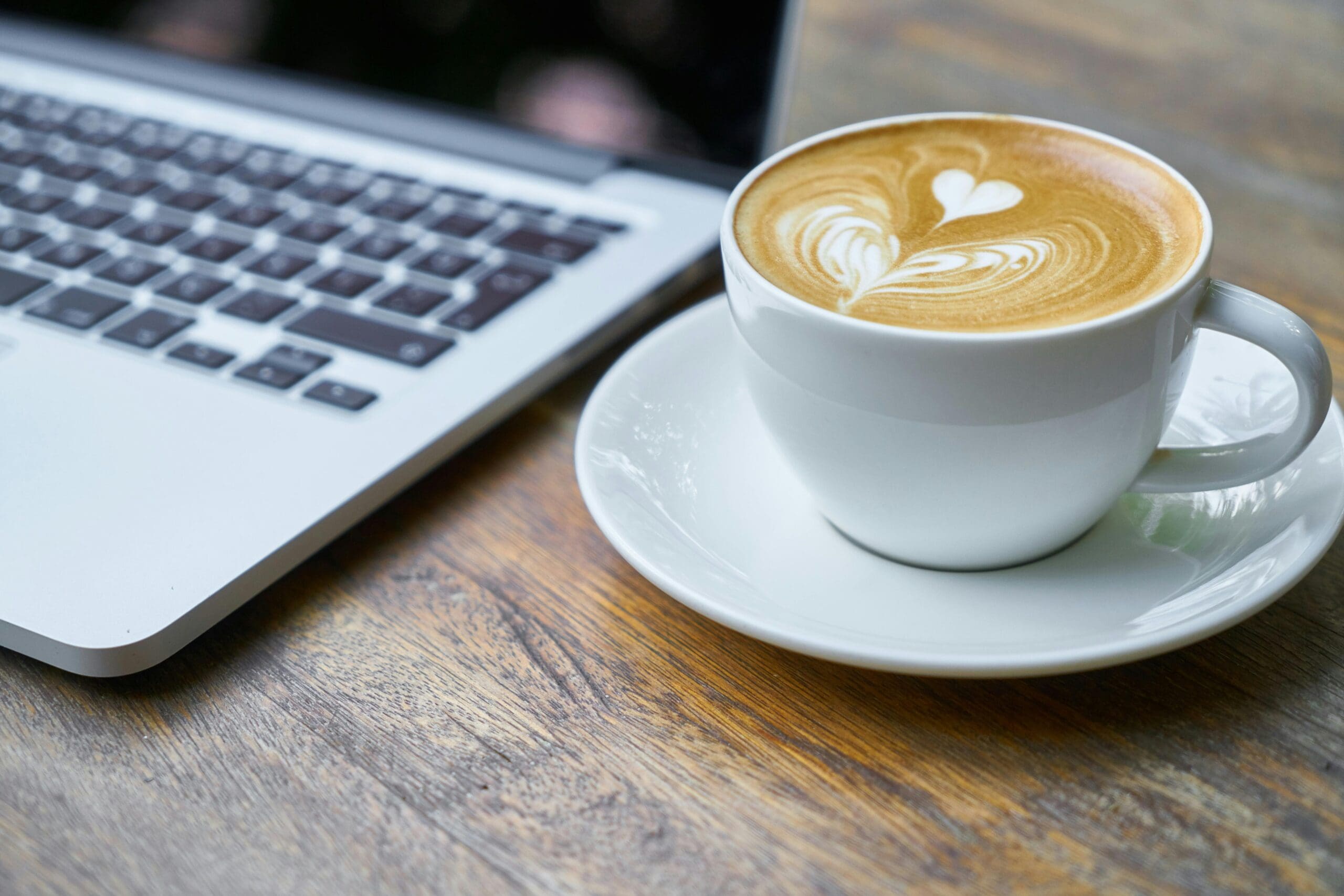 laptop and coffee with pretty swirled heart in cream