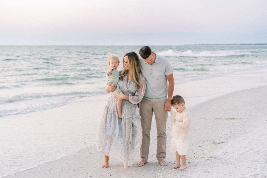 Family with small children walking on beach. 
