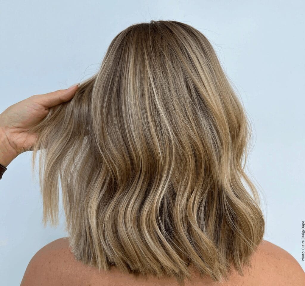 Back view of a blonde woman's soft, wavy lob haircut