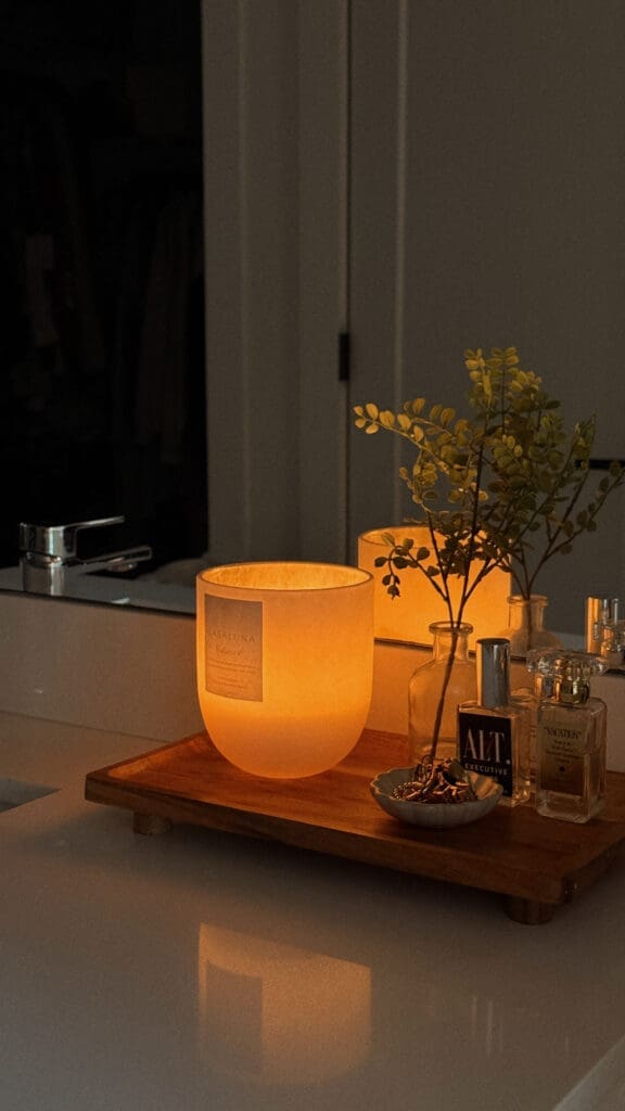 candle burning near perfume to create a summer home fragrance