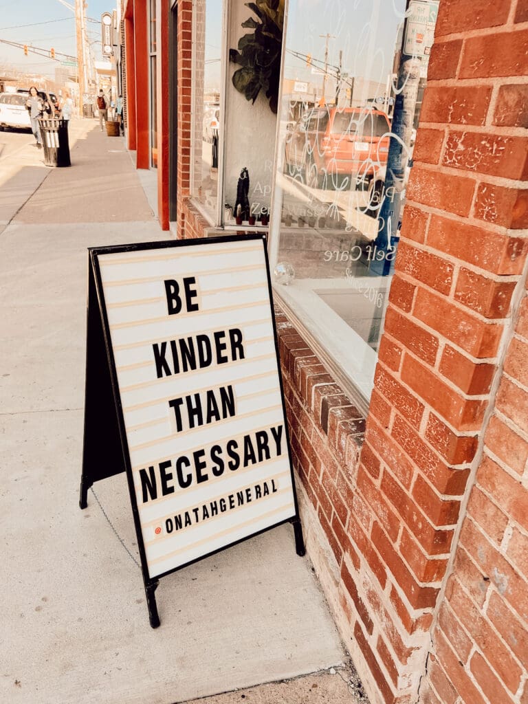 Sign reading, "Be Kinder Than Necessary"